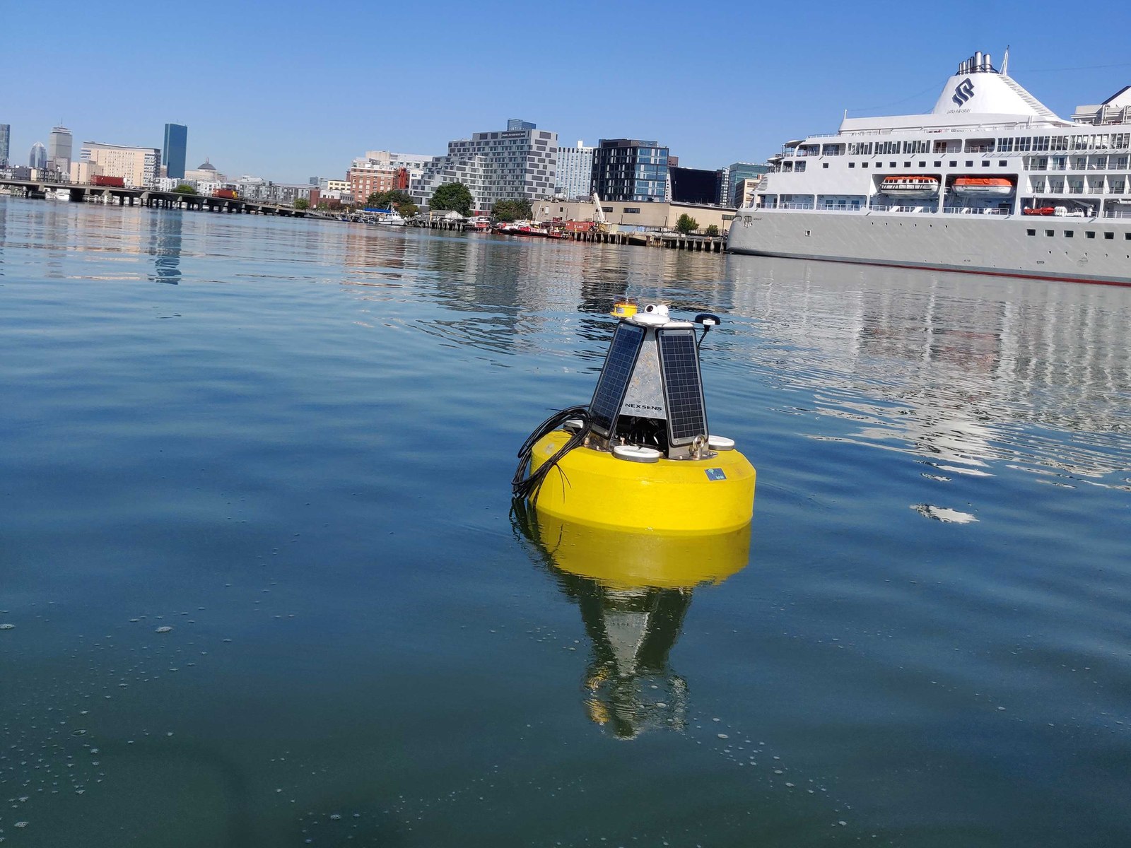 HydroBuoy on station in Boston Harbor, city skyline and a ship behind